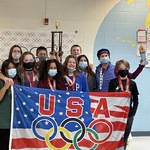 students smiling with USA flag in front of them