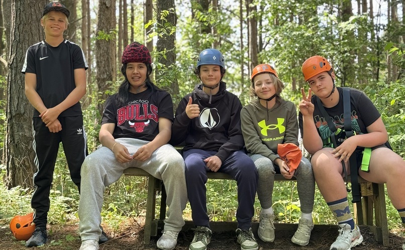 group of students sitting and standing in woods