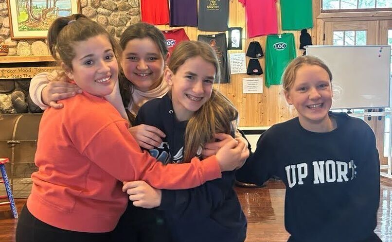 girls smiling and hugging in a lodge